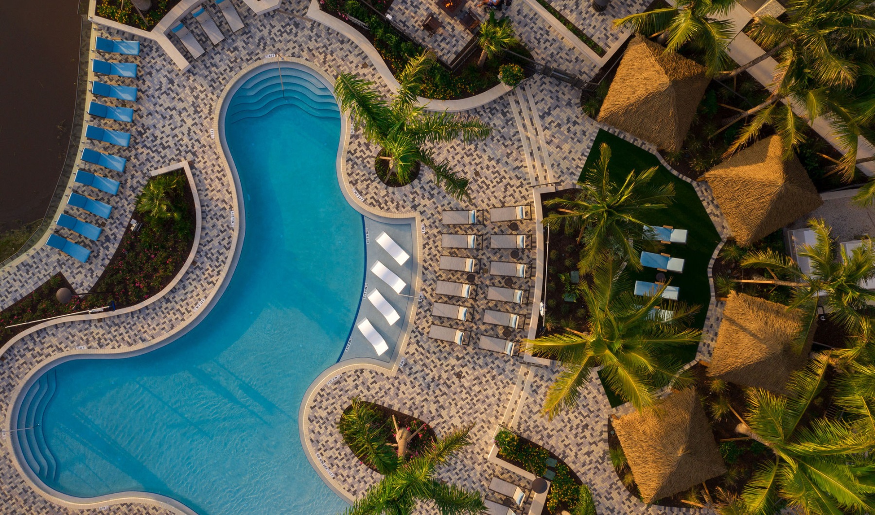 Aerial of Pool Space aerial photo of pool area with water lounger chairs and resort style cabanas